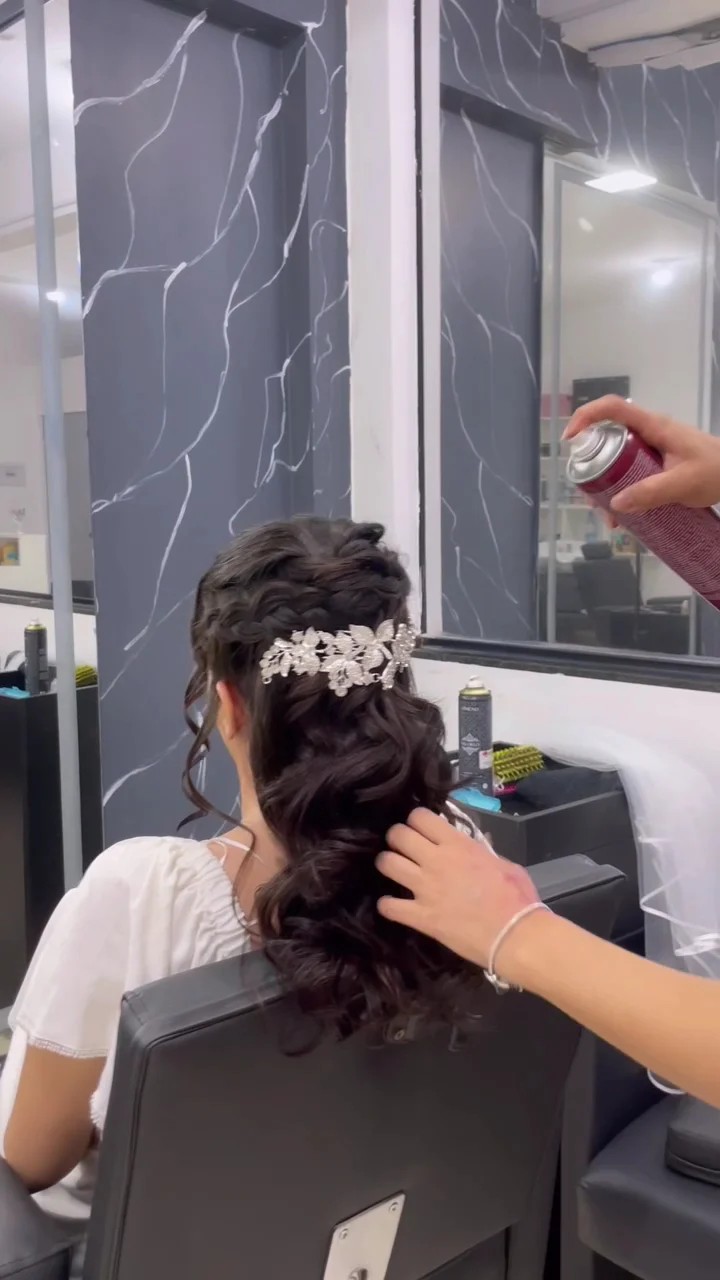 Noiva sentada na cadeira do estúdio enquanto o penteado com tiara recebe os últimos ajustes