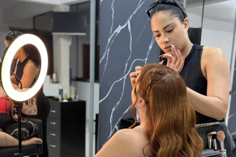 Estúdio com ring light acesa enquanto uma cliente tem o cabelo trançado