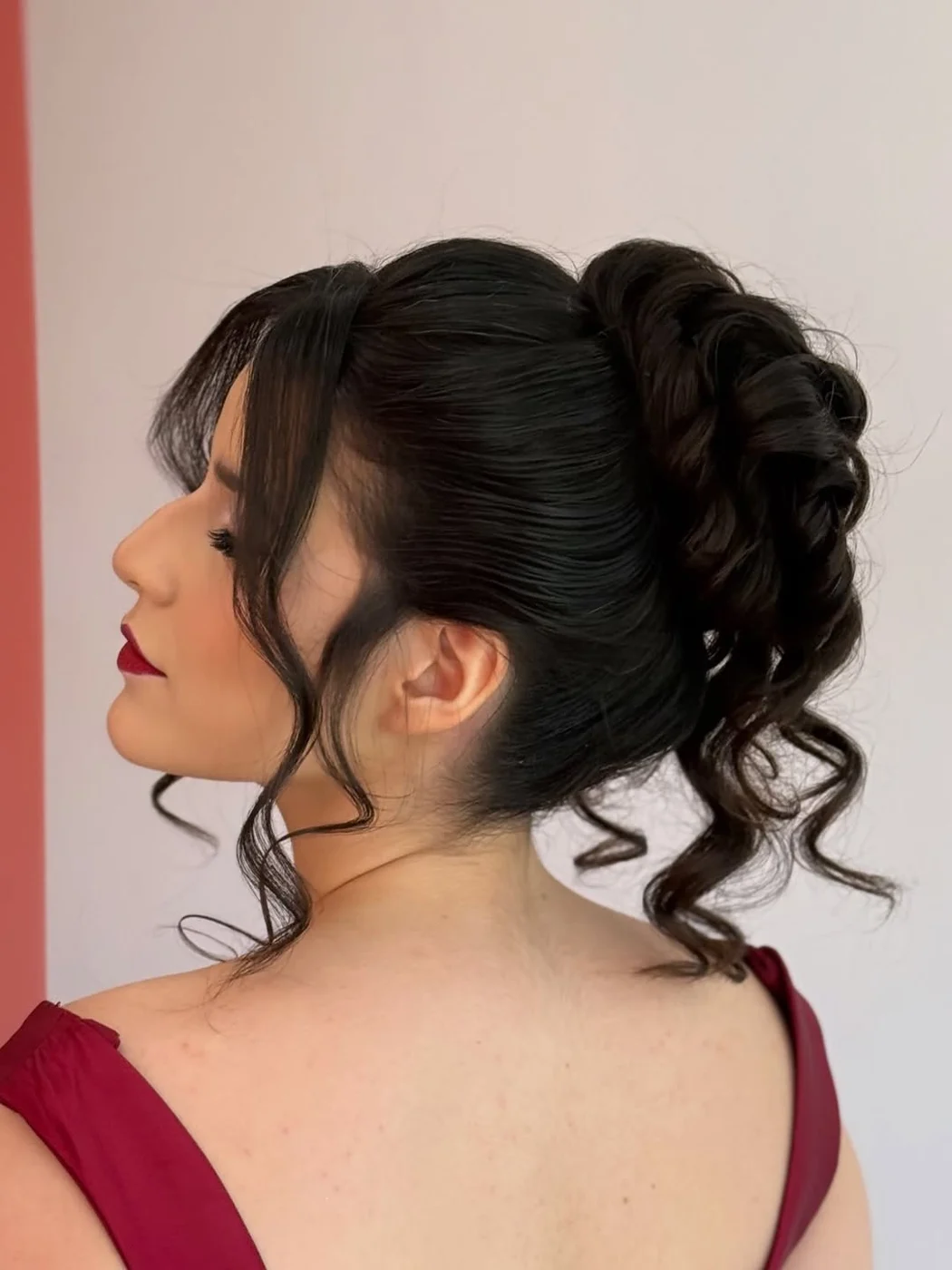 Coque despojado com mechas soltas e franja, visto de perfil