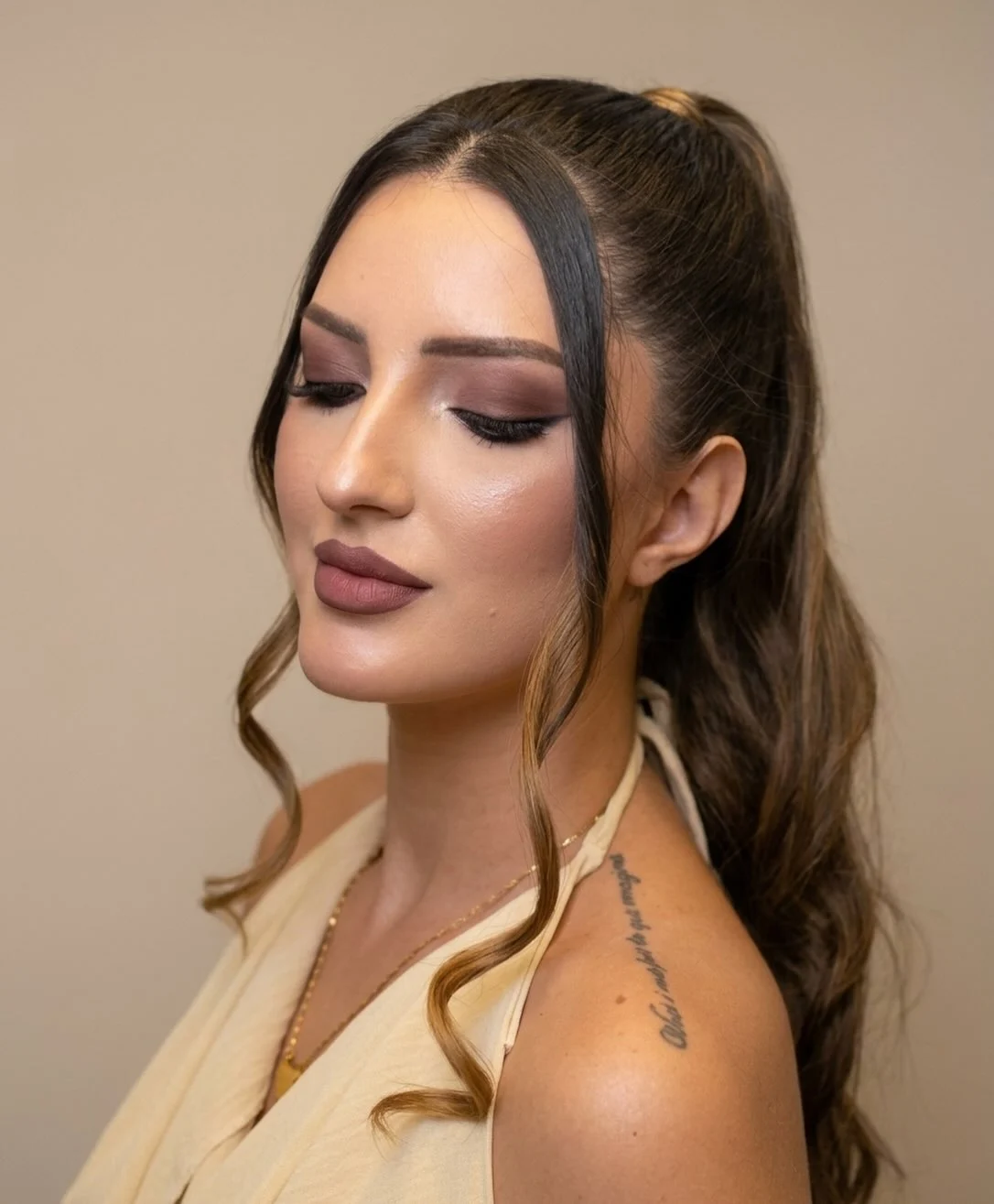 Cliente de olhos fechados mostrando sombra marrom esfumada, cabelo em rabo alto ondulado
