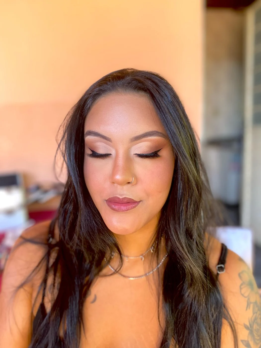 Cliente de olhos fechados mostrando a sombra esfumada e o batom rosado, com a pele iluminada pela luz do dia
