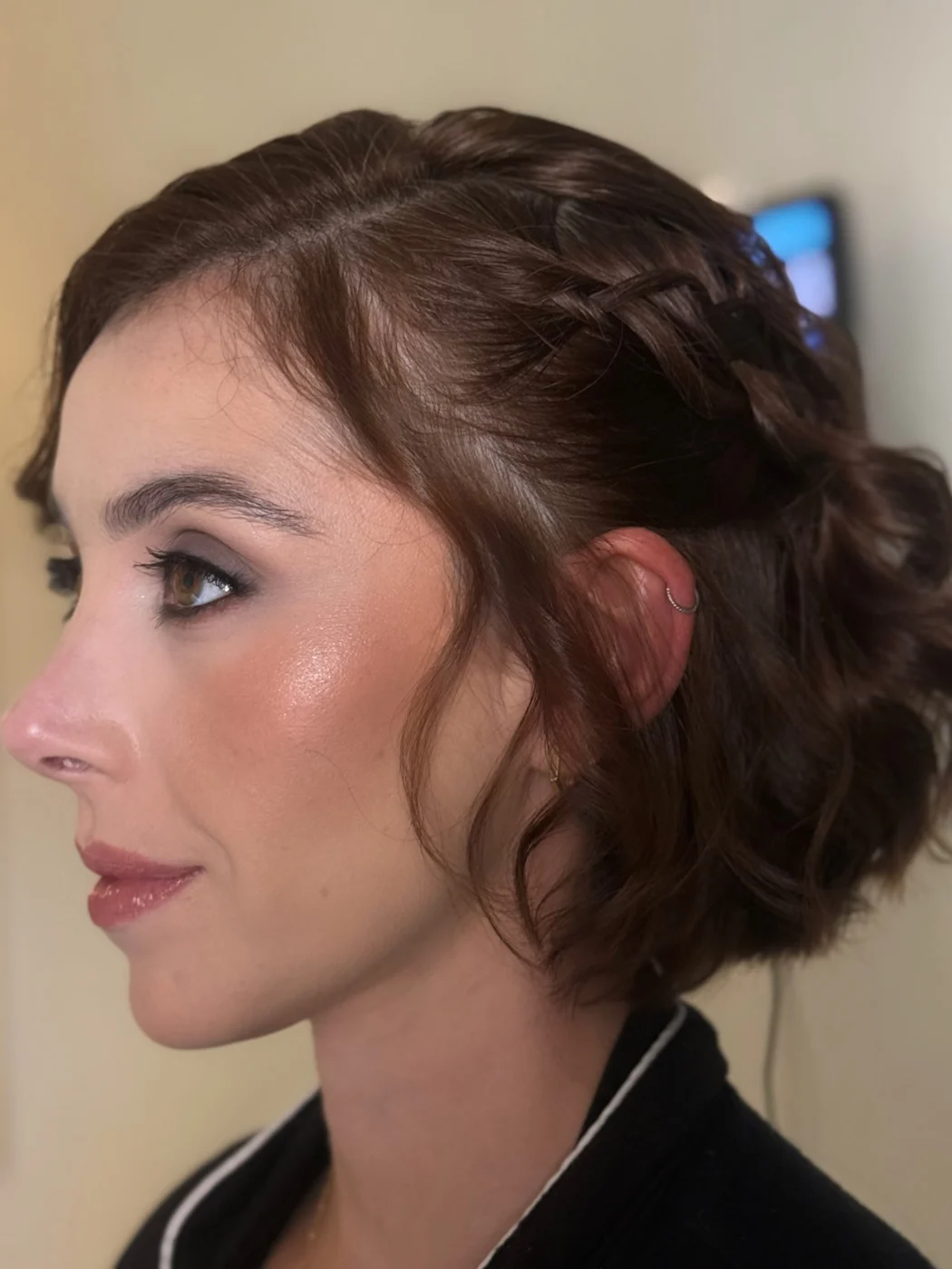 Cliente de perfil, cabelo castanho preso com trança, pele iluminada e olhos esfumados
