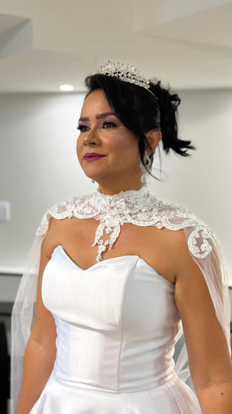 Noiva de tiara e capa de renda, com maquiagem pronta e cabelo preso